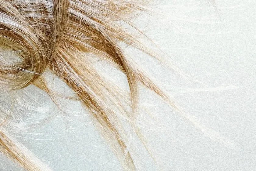 Fine blonde strands of hair resting against a pale surface