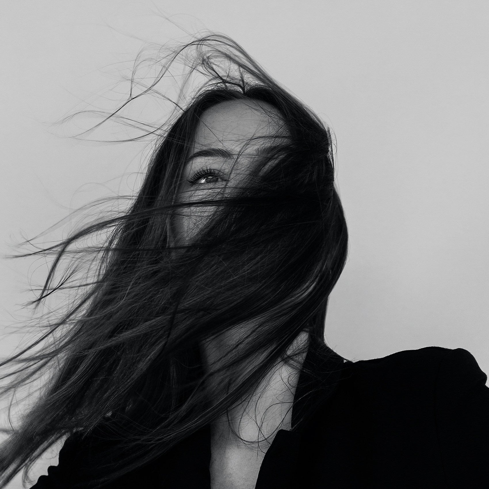 Woman with long hair blowing in the wind against a plain background