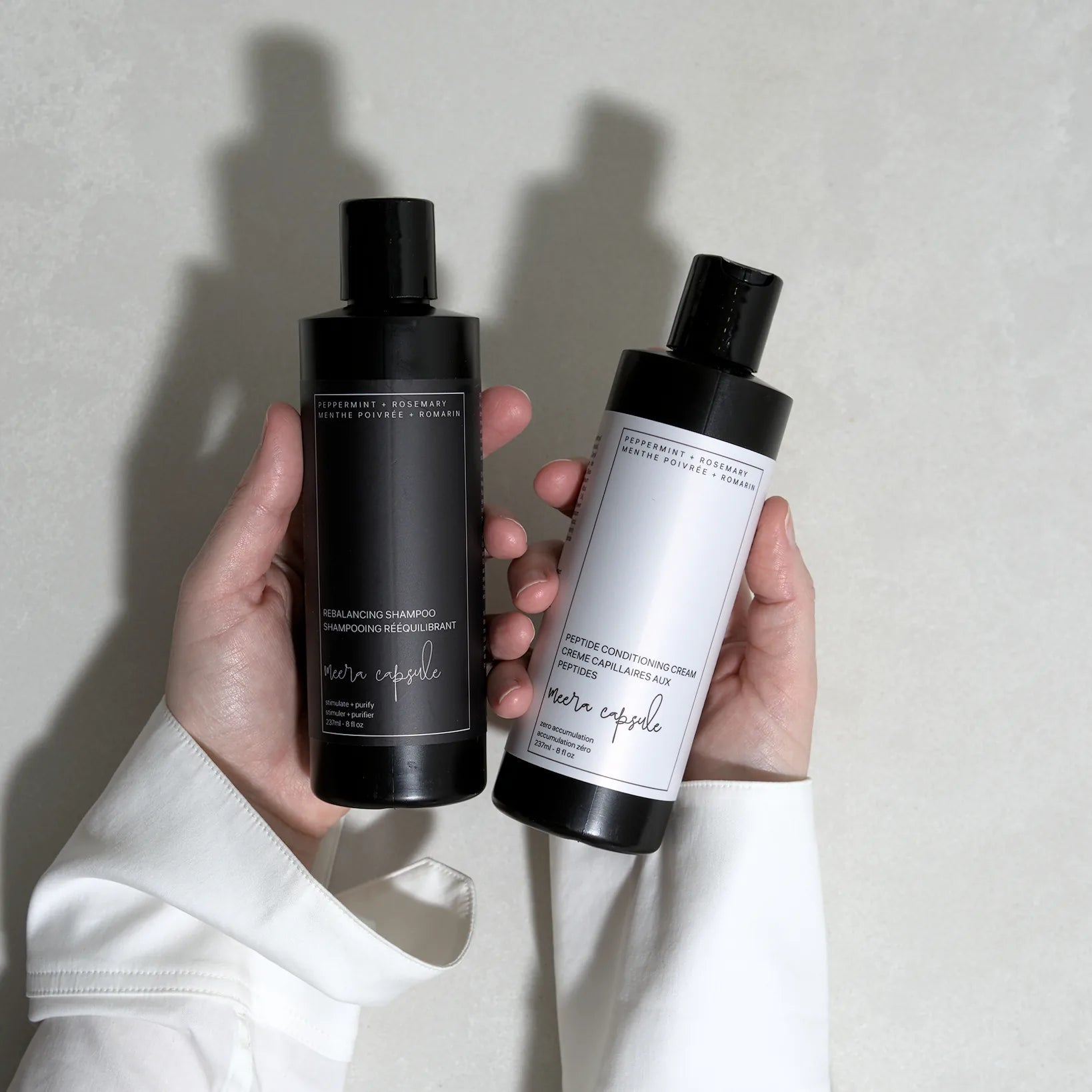 Meera Capsule Shampoo + Conditioner Bundle close-up — amber glass bottles with minimalist labels on neutral background